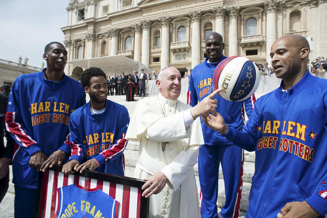 Pope Francis smiles as he plays with a basketball next to a member of the Harlem Globetrotters basketball team during the weekly audience in Saint Peter's Square at the Vatican May 6, 2015.  REUTERS/Osservatore Romano   ATTENTION EDITORS - THIS PICTURE WA