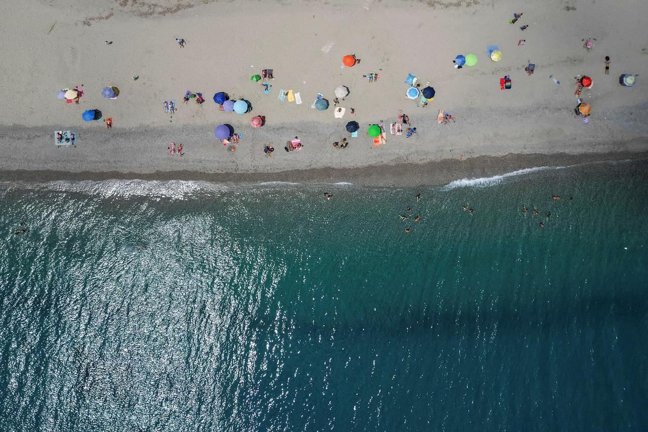 A drone view shows parasols and people enjoying the beach during warm weather in Messina
