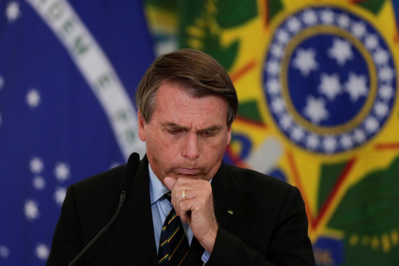 Brazil's President Jair Bolsonaro coughs during a ceremony to announce measures by Caixa Economica bank in support of philanthropic hospitals, in Brasilia