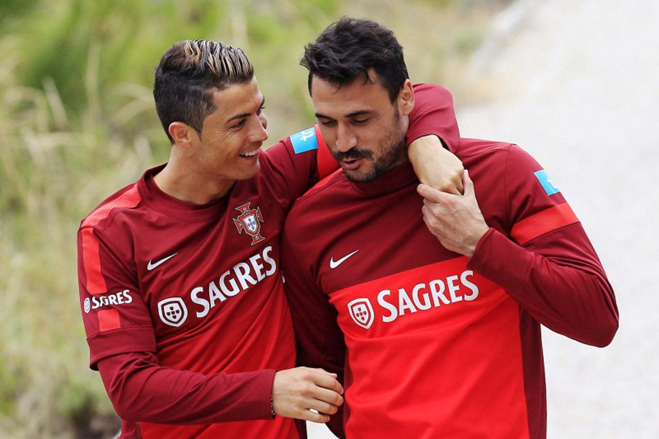 'Portugal's Cristiano Ronaldo (L) talks with teammate Hugo Almeida upon arriving at a training session in Obidos June 6, 2013. Portugal will play against Russia in their 2014 World Cup qualifying soc