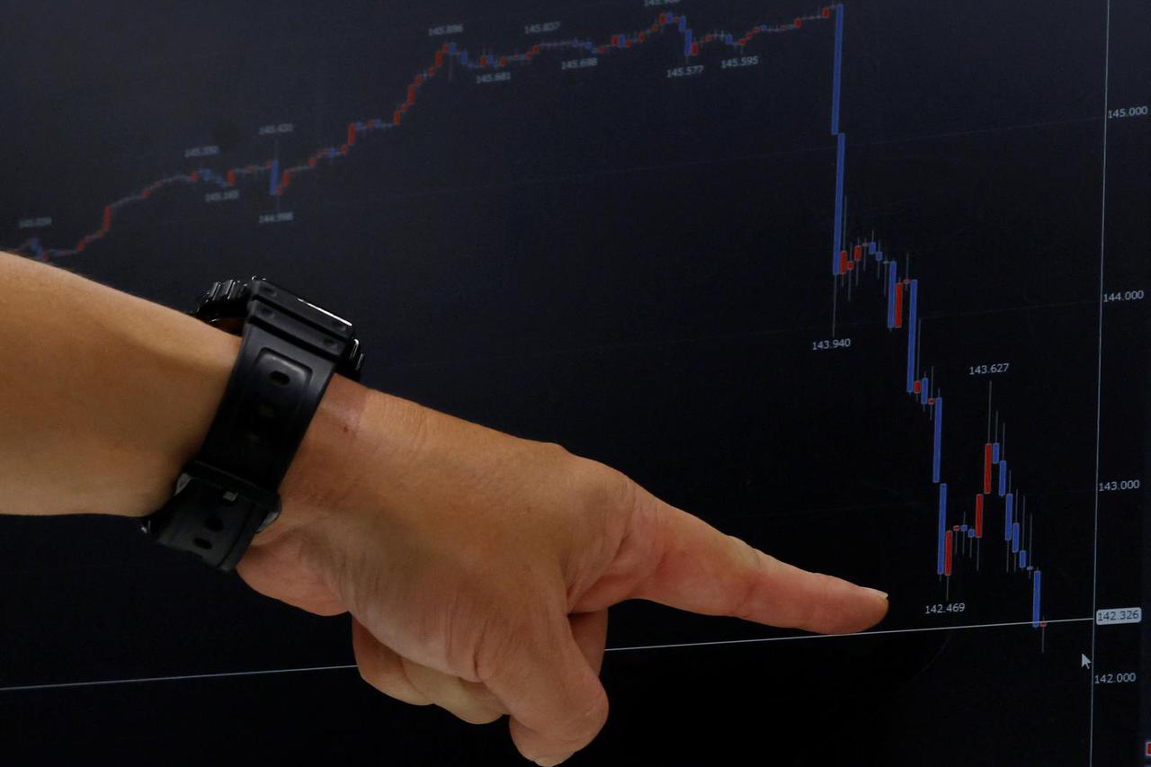 A journalist points out a graph of the Japanese yen exchange rate against the U.S. dollar on a monitor