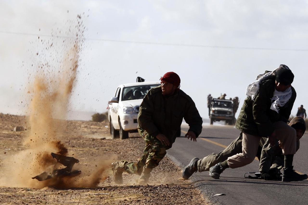 Rebel fighters jump away from shrapnel during heavy shelling by forces loyal to Libyan leader Muammar Gaddafi near Bin Jawad in this March 6, 2011 file photo. Rebels in east Libya had regrouped and advanced on Bin Jawad after forces loyal to Muammar Gadda