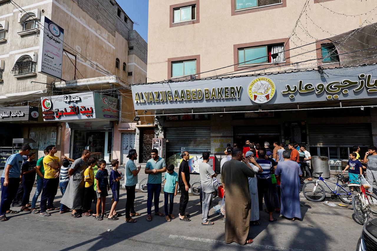 Palestinians wait to buy bread outside a bakery in Khan Younis