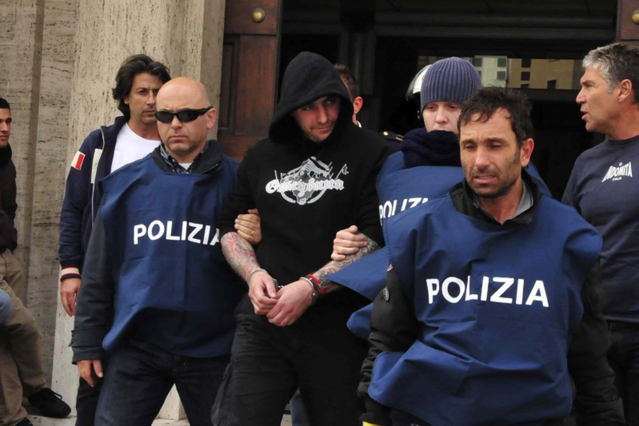 \'A man identified as Ivan Bogdanov (2nd L), a Serbian national team supporter who is believed to be the ringleader of crowd violence, is detained outside the Luigi Ferraris stadium in Genoa October 1