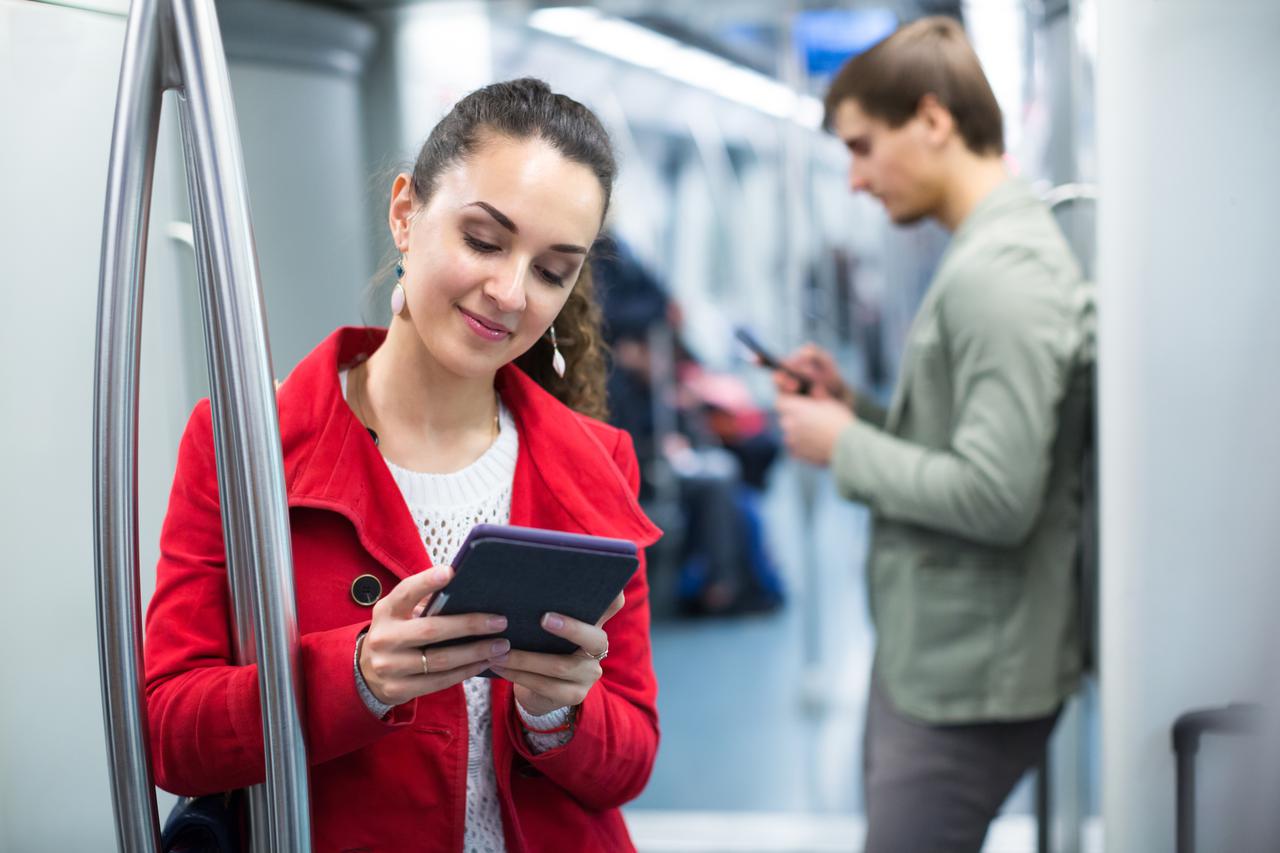 Young subway tourists busy with modern phones and tablet