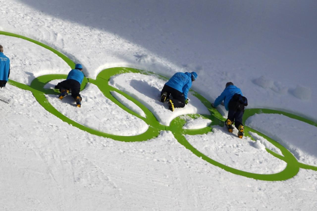 'Workers adjust the Olympic rings at the landing hill of the K95 ski jump at Whistler Olympic Park during preparations for the Vancouver 2010 Winter Olympics in Whistler, British Columbia, February 6,