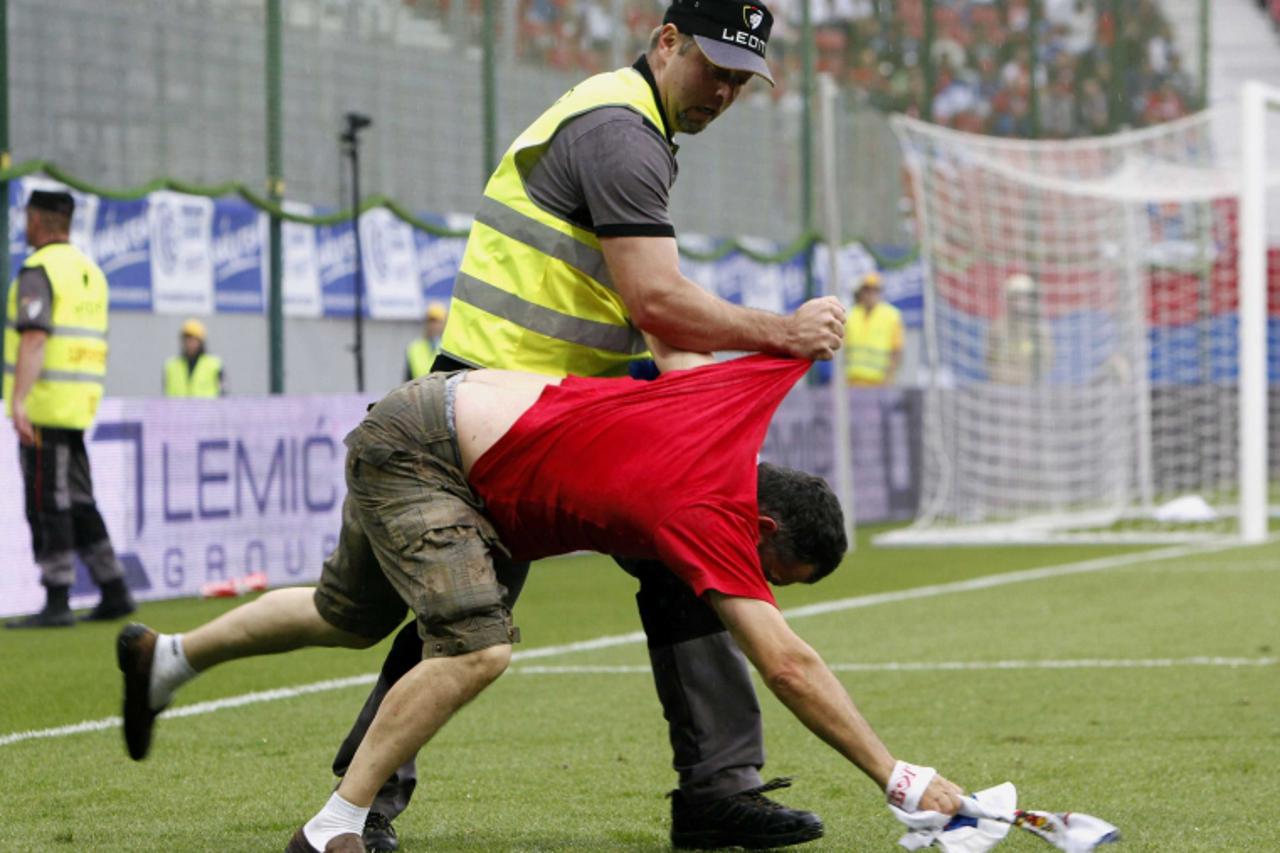 'A supporter of Serbia is grabbed by security personnel after entering the pitch during the international friendly soccer match between Serbia and New Zealand in Klagenfurt May 29, 2010.   REUTERS/Rob
