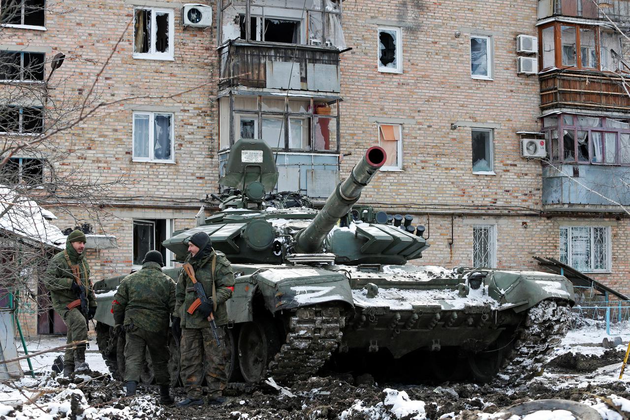 Service members of pro-Russian troops are seen next to a tank outside a residential building which was damaged during Ukraine-Russia conflict in Volnovakha