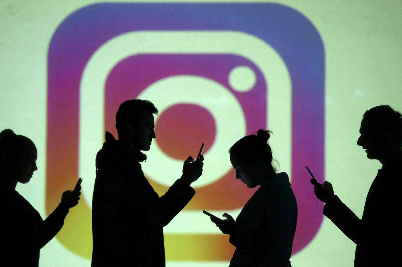 FILE PHOTO: Silhouettes of mobile users are seen next to a screen projection of Instagram logo in this picture illustration