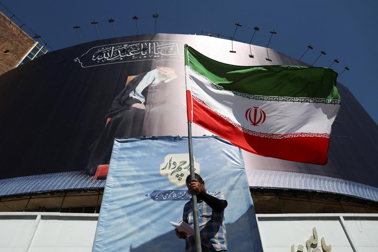 A man holds an Iranian flag on a street, in Tehran