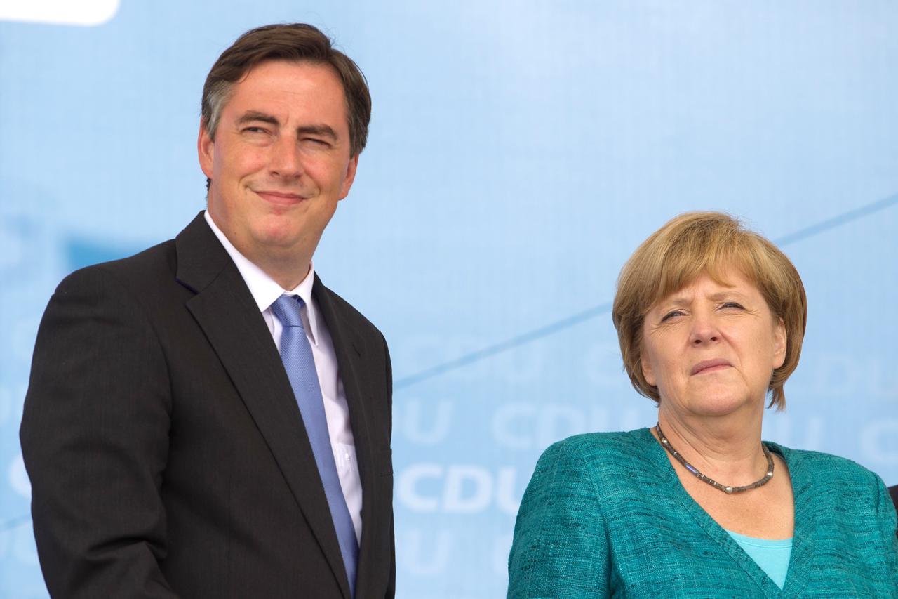 German chancellor Angela Merkel (CDU) waves onstage at an election campaign event in East Frisian fisher village Neuharlingersiel, Germany, 19 July 2013. Former premier of Lower Saxony, David McAllister (CDU), stands next to her. The party leader visits d