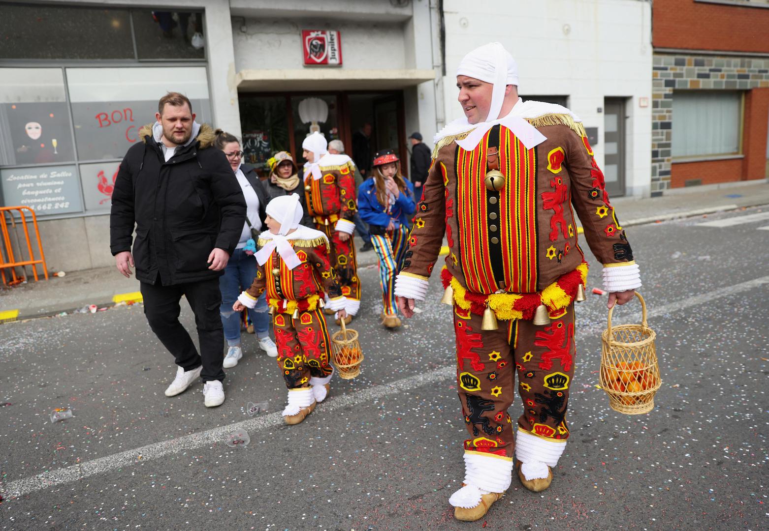 People wearing costumes walk near the site where a vehicle drove into a group of Belgian carnival performers who were preparing for a parade in the village of Strepy-Bracquegnies, Belgium March 20, 2022. REUTERS/Johanna Geron Photo: JOHANNA GERON/REUTERS