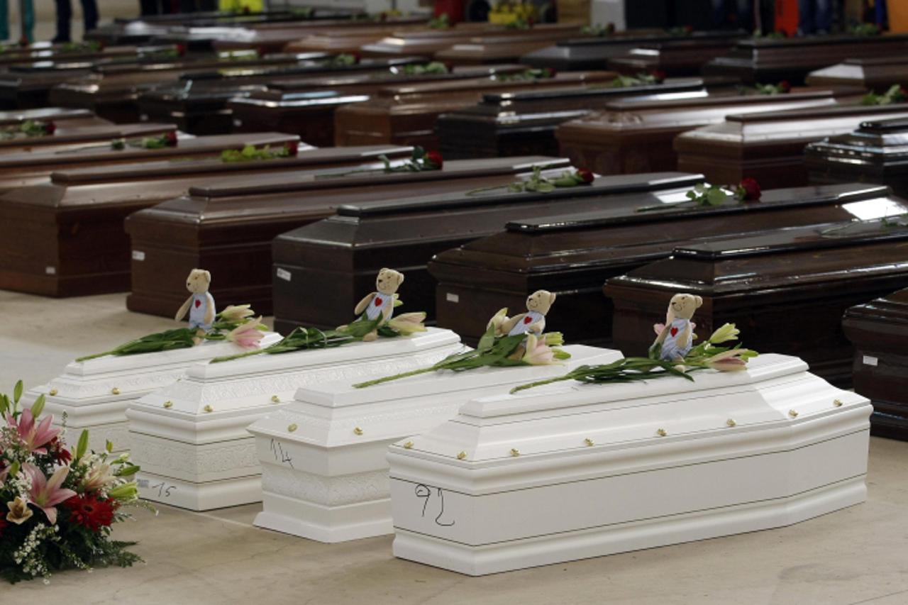 'Coffins (in white) of children are seen alongside coffins of other victims from a shipwreck off Sicily, in a hangar of the Lampedusa airport October 5, 2013. Rough seas again blocked efforts to recov