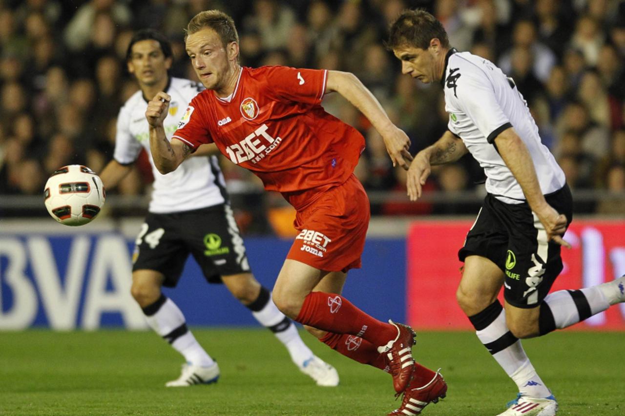 'Sevilla\'s Ivan Rakitic (C) and Valencia\'s Joaquin Sanchez fight for the ball as Tino Costa watches during their Spanish first division soccer match at the Mestalla Stadium in Valencia, March 20, 20