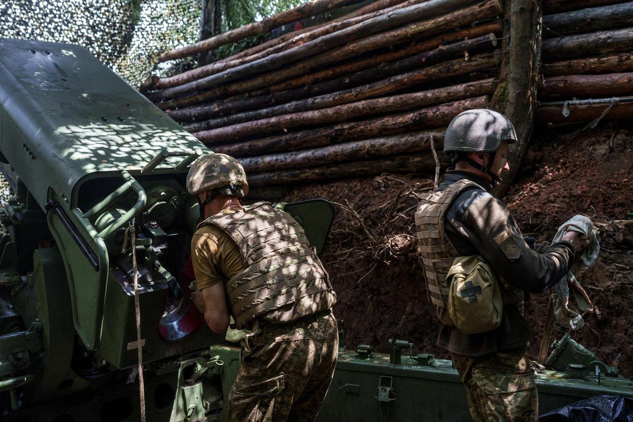 Ukrainian service members prepare a howitzer before fire towards Russian troops, at a position in a front line in Kharkiv region