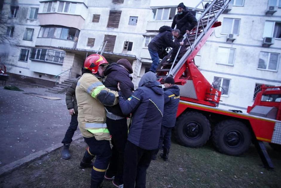 Rescuers help people to be evacuated from a residential building damaged by shelling in Kyiv