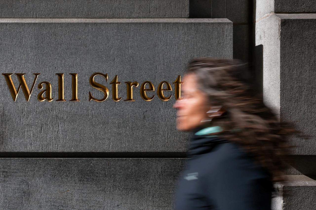 FILE PHOTO: A woman walks down Wall Street in New York
