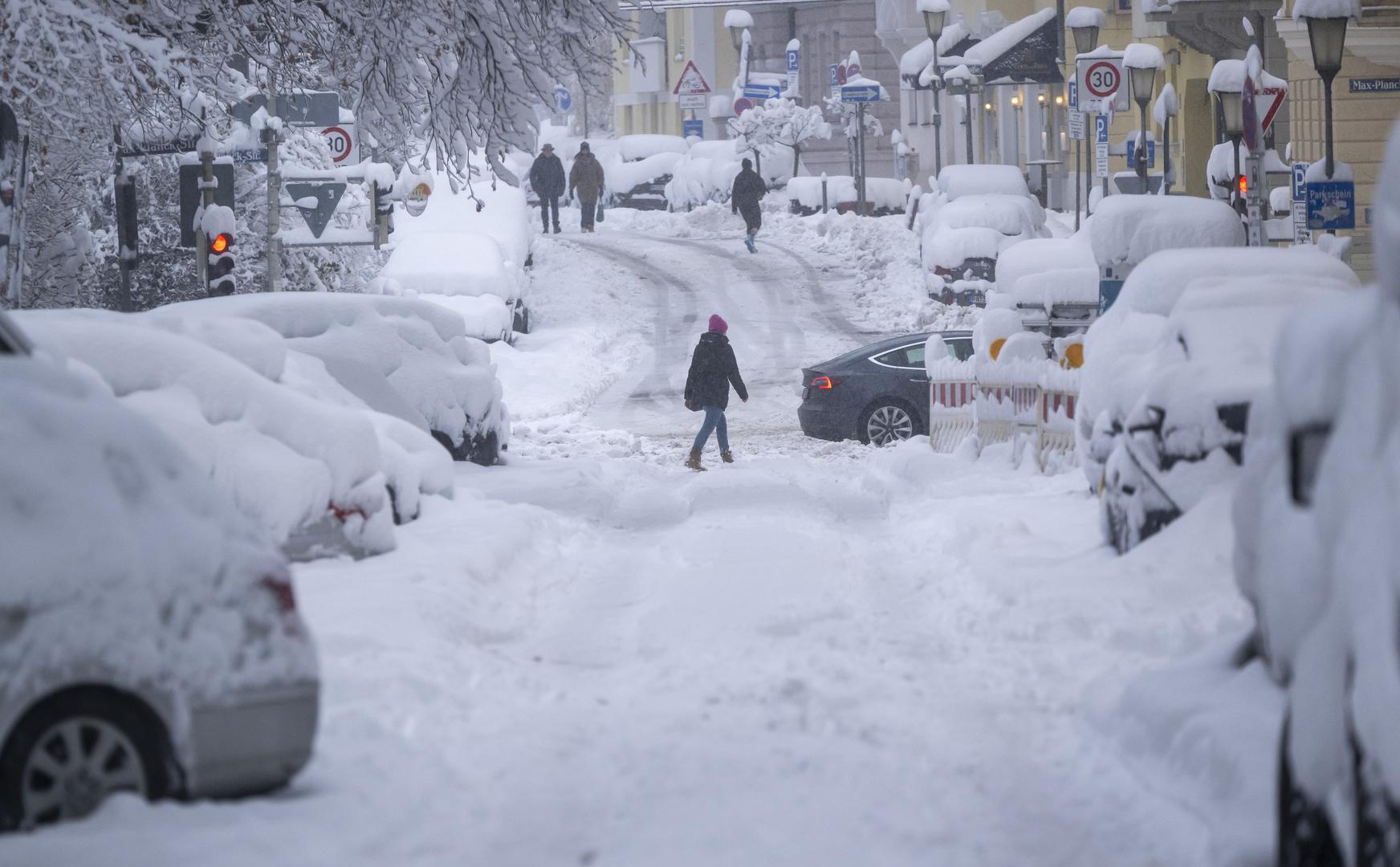 02 December 2023, Bavaria, Munich: Passers-by walk along a snow-covered road. Snow and ice have caused chaos on the roads and on the railroads in southern Bavaria. Photo: Peter Kneffel/dpa Photo: Peter Kneffel/DPA