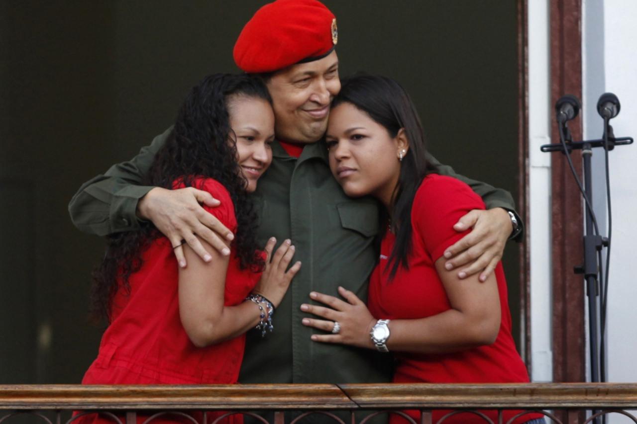 'Venezuela's President Hugo Chavez hugs his daughters Rosa (L) and Maria while appearing to supporters on a balcony of Miraflores Palace soon after his return to the country from Cuba, where he under