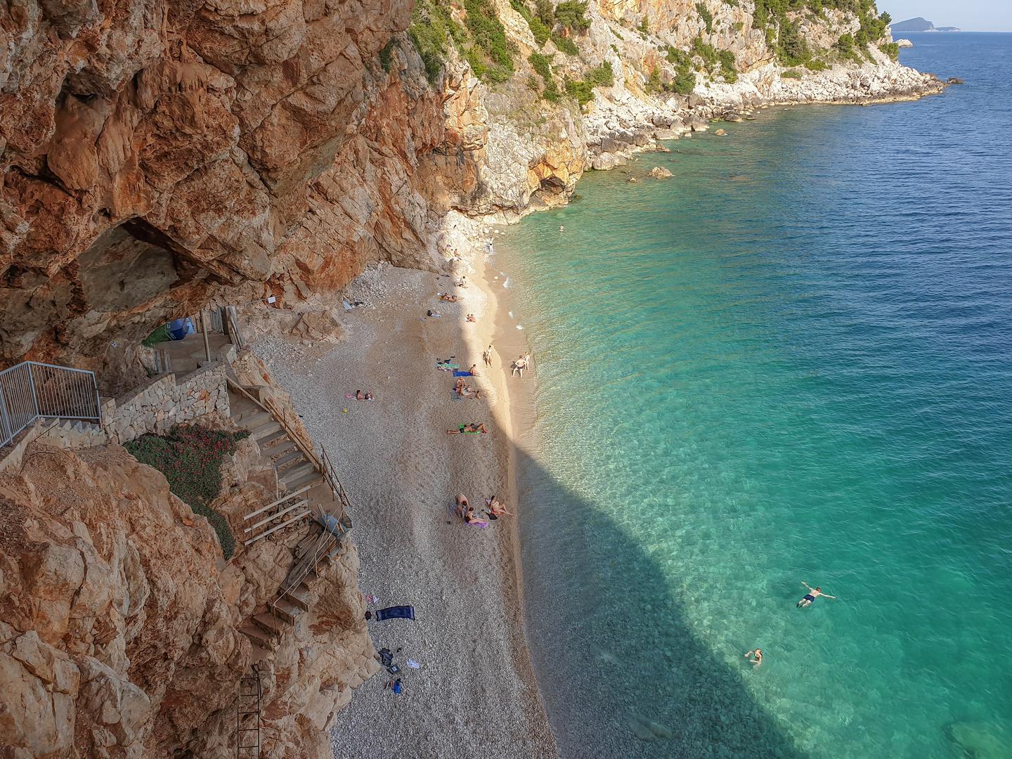 09.06.2019., Popovici, Konavle - Plaza Pasjaca jedna je od najljepsih plaza na citavom Jadranu. Ova pjescana plaza smjestila se u Konavlima, ispod sela Popovici, tridesetak kilometara udaljenog od Dubrovnika prema granici s Crnog Gorom. Plaza nije prirodna. Nastala je bacanjem kamenja tijekom Drugog svjetskog rata kada su se u okolnim selima kopali tuneli. More je kamenje usitnilo i napravilo predivnu plazu koja stidljivo izlazi ispod ogromnih litica Konavoskih stijena.rPhoto: Grgo Jelavic/PIXSELL