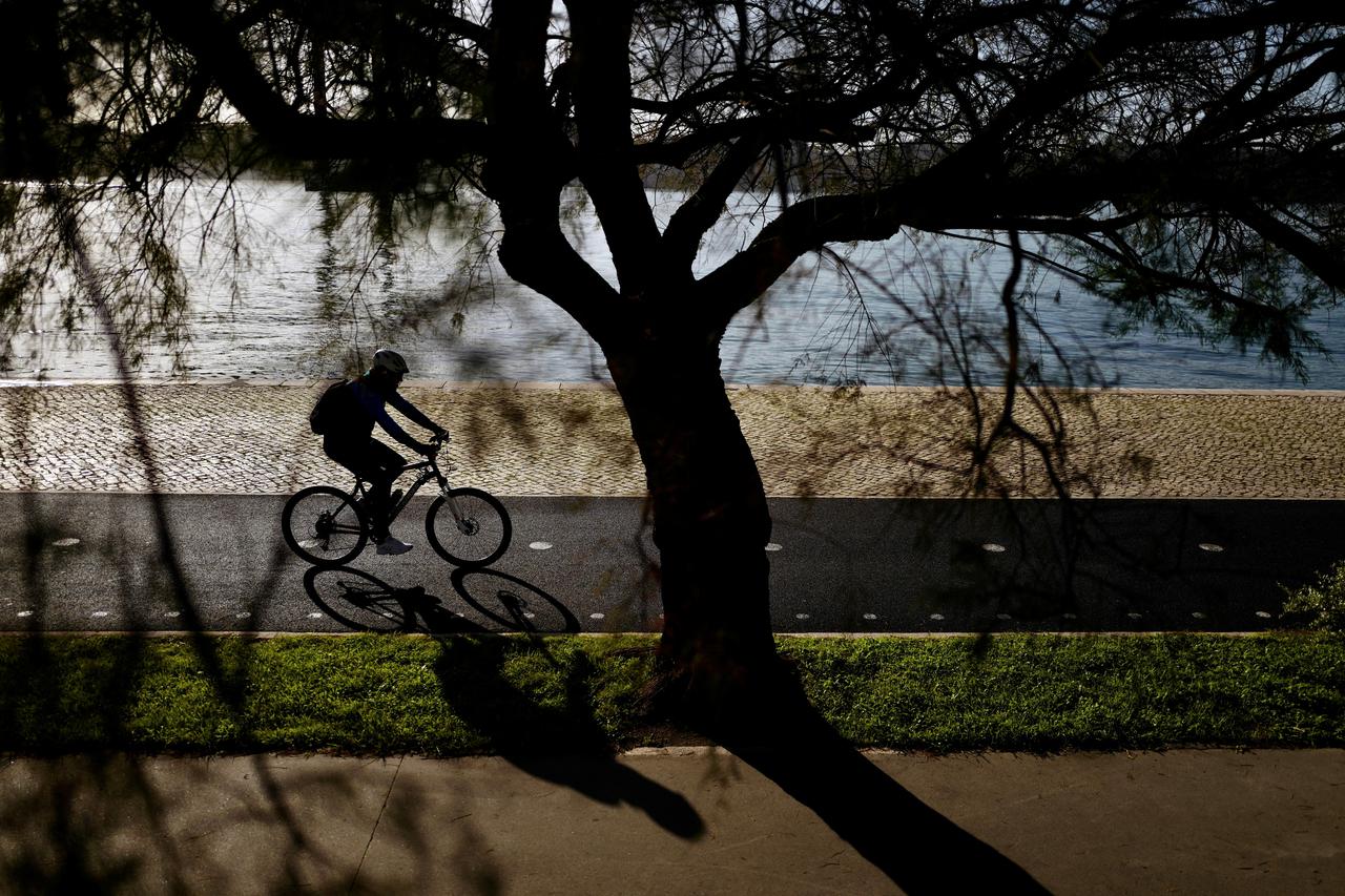 A person rides a bike near Tagus river in Lisbon