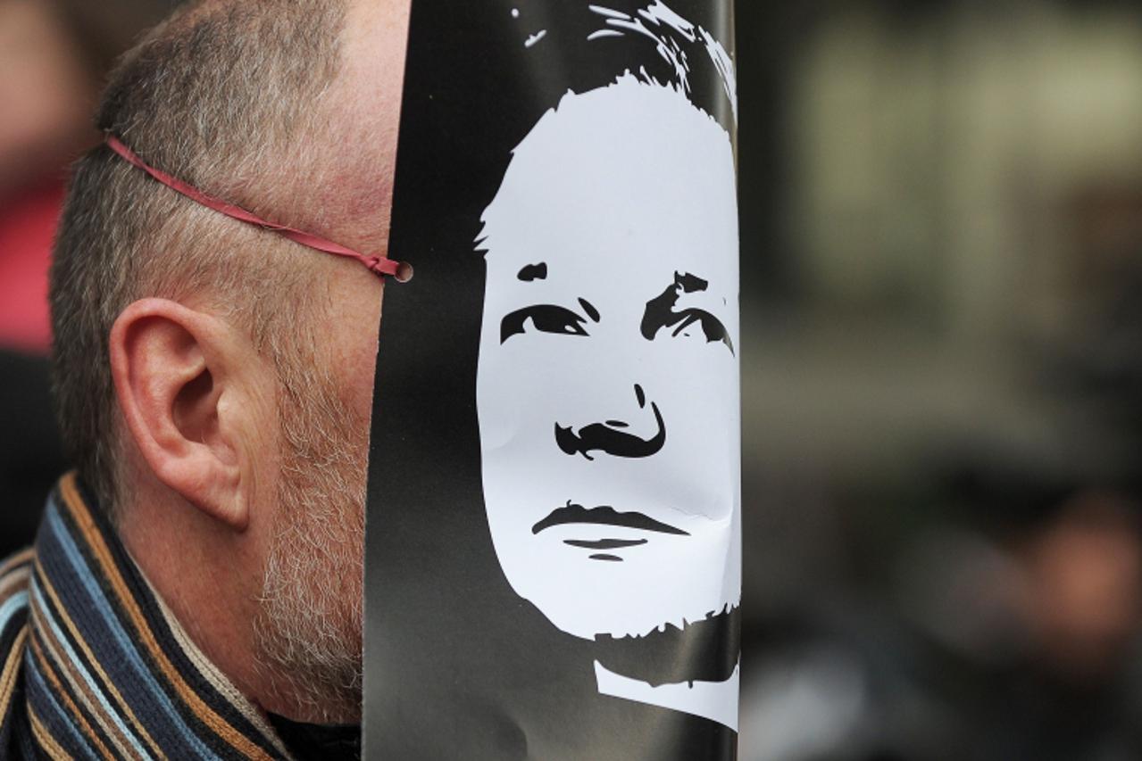 'A demonstrator wears a mask depicting the face of the WikiLeaks founder, Julian Assange, during a protest over his arrest, outside the City of Westminster Magistrates\' Court in central London, on De