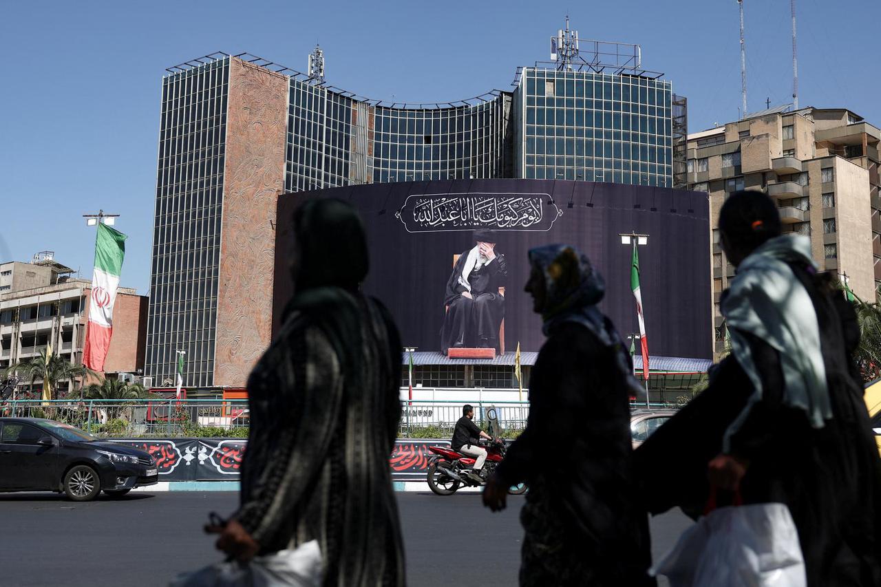 People walk past a billboard with a picture of the late Iran's Supreme Leader Ayatollah Ali Khamenei, in Tehran