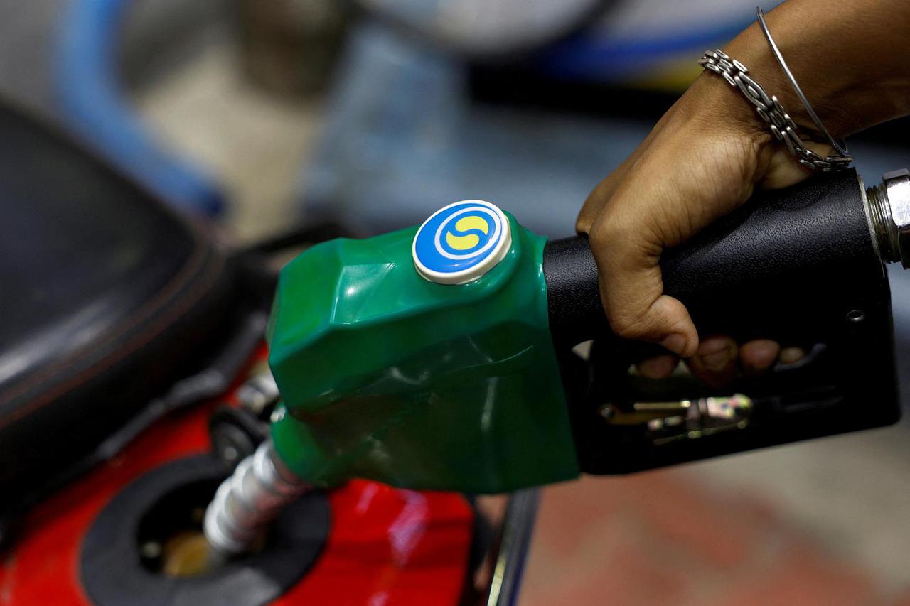 FILE PHOTO: A worker holds a nozzle to pump fuel into a two-wheeler vehicle at a Bharat Petroleum oil and fuel station in Kolkata