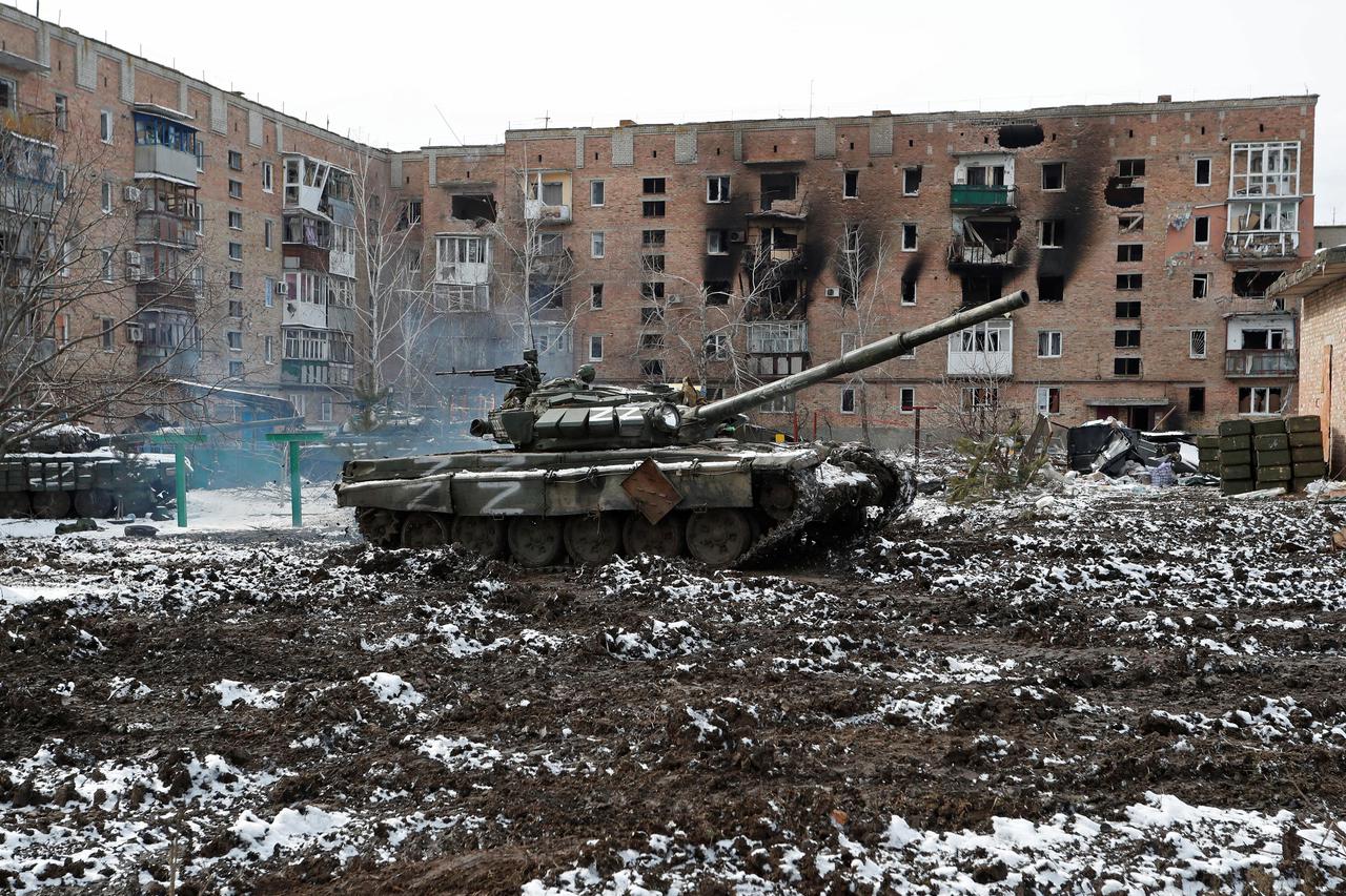 A tank with the letters "Z" painted on it is seen in front of a residential building which was damaged during Ukraine-Russia conflict in Volnovakha