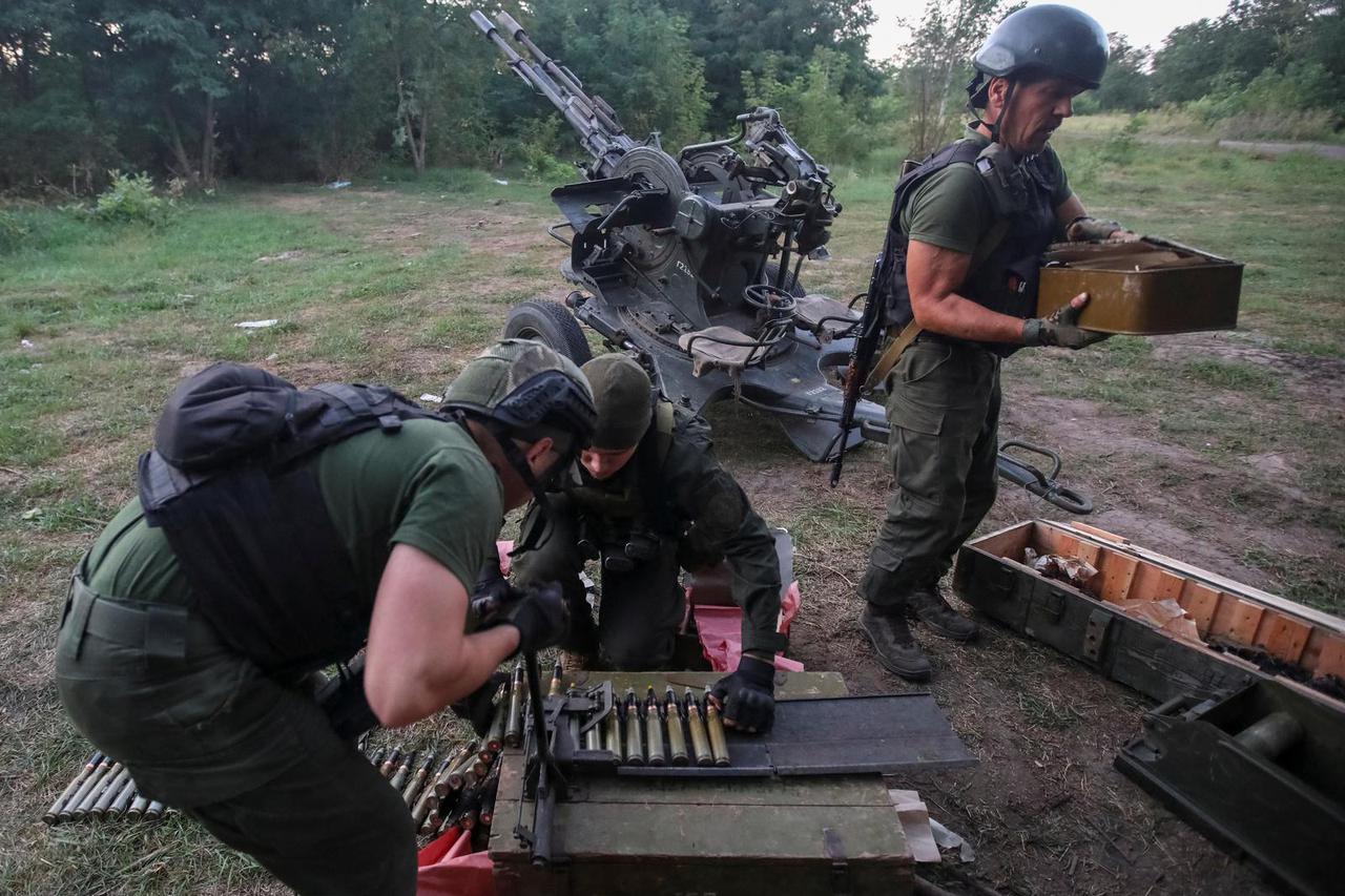Ukrainian servicemen load projectiles into a weapon belt next to a ZU-23-2 anti-aircraft cannon at position near a front line in Kharkiv region