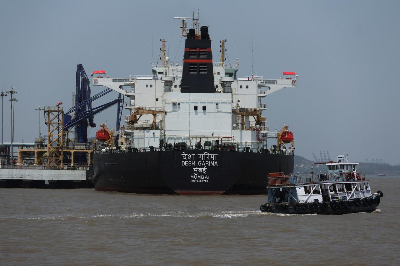 A ferry moves past India-flagged tanker Desh Garima, as it unloads crude oil at an offloading terminal after transiting the Strait of Hormuz, amid supply disruptions linked to the U.S.-Israeli conflict with Iran, in Mumbai