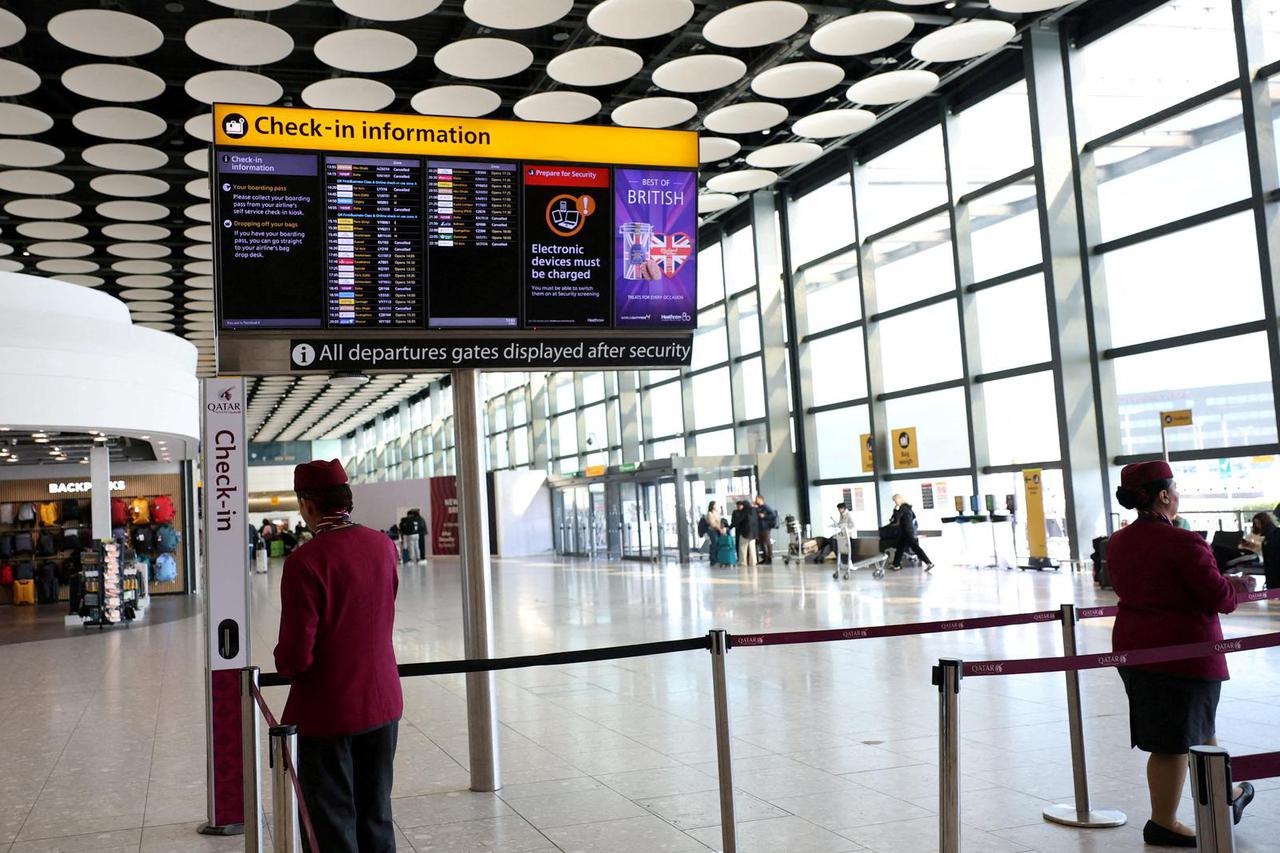 FILE PHOTO: FILE PHOTO: Qatar airline staff stand by a departure board displaying cancelled flights to Middle East countries amid the U.S.-Israel conflict with Iran, at Heathrow Airport