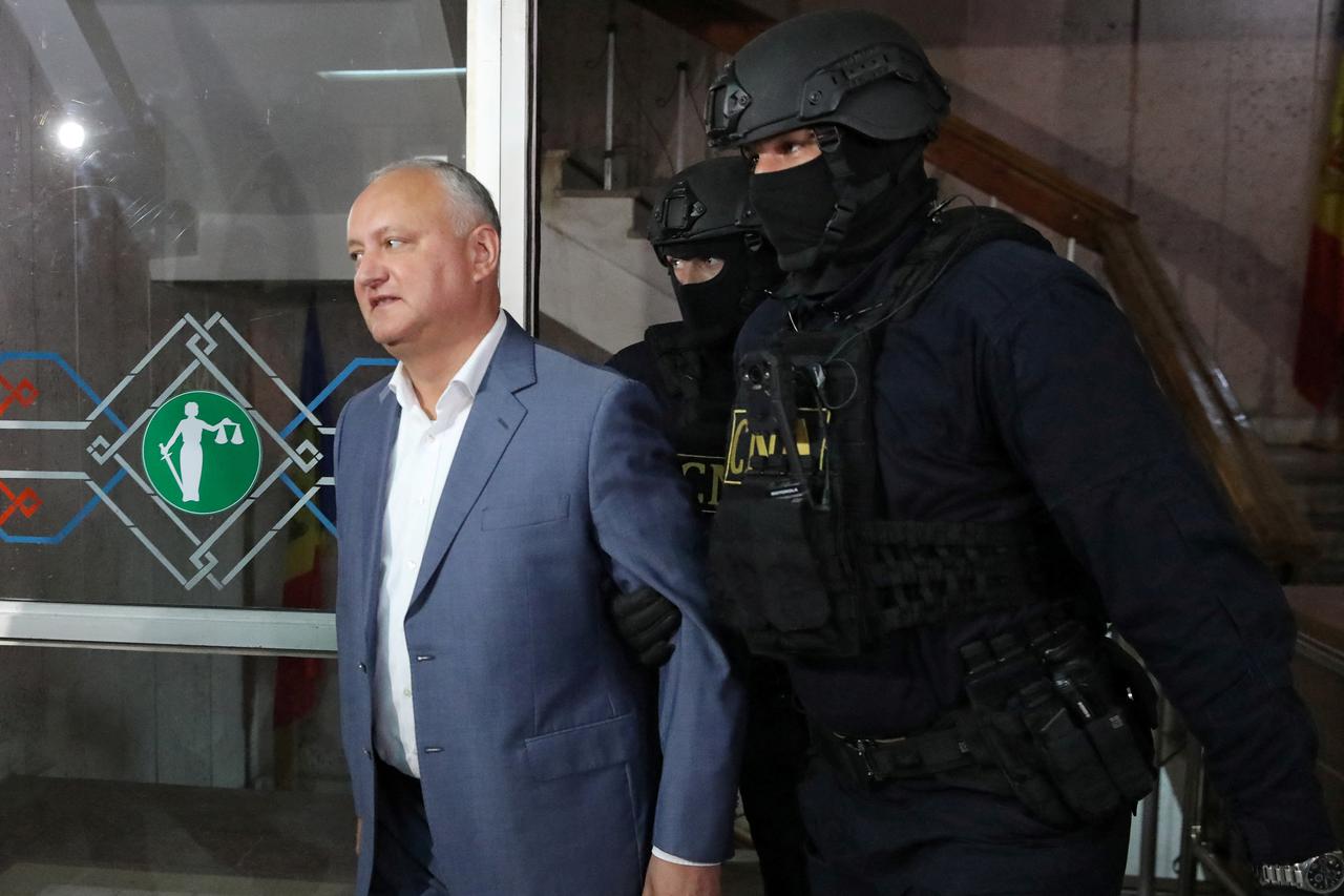 Moldova's former President Igor Dodon is escorted by law enforcement officers before a court hearing in Chisinau