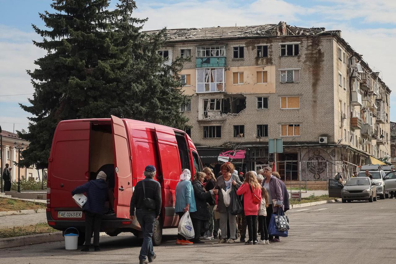 Local residents crowd near a car distributing humanitarian aid in the town of Izium