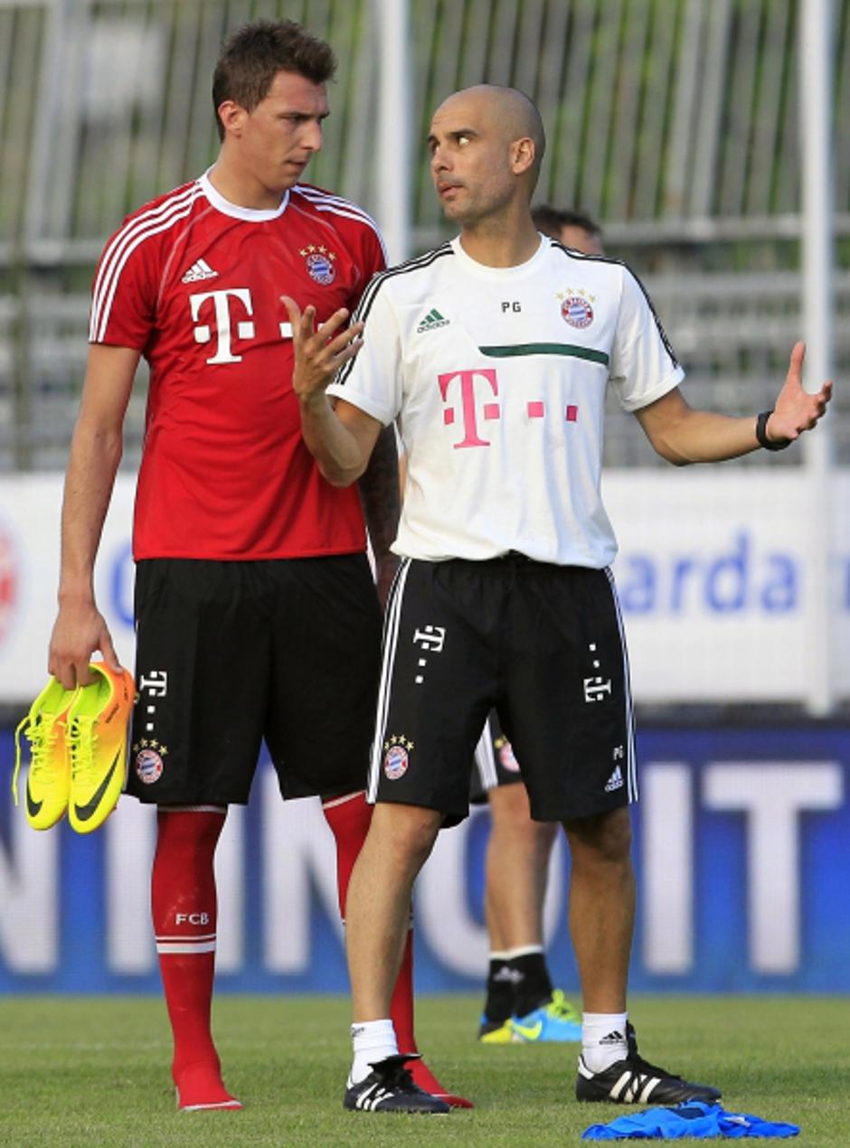 'Bayern Munich\'s head coach Pep Guardiola (R) gestures as he talks with his player Mario Mandzukic during a training session in Arco, northern Italy July 4, 2013. REUTERS/Alessandro Garofalo (ITALY -