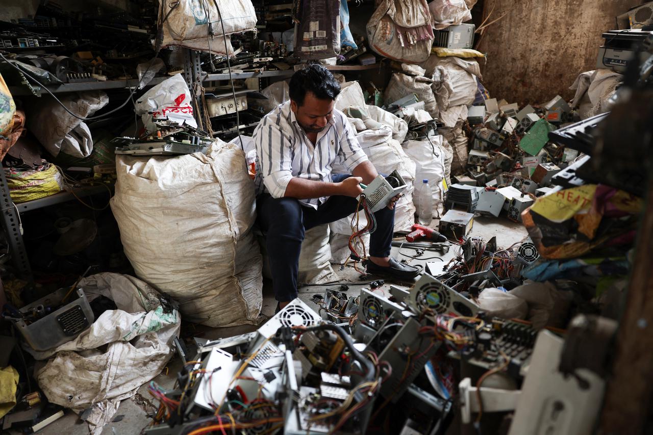 A man recycles electronic waste or e-waste from the power supply of computers at a scrap yard in Ahmedabad