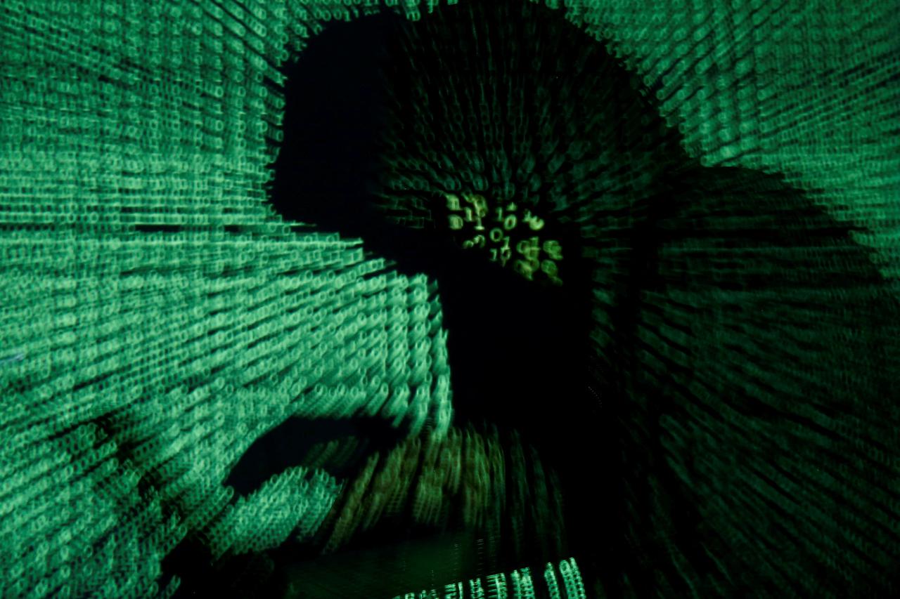 FILE PHOTO: Man holds laptop computer as cyber code is projected on him in this illustration picture