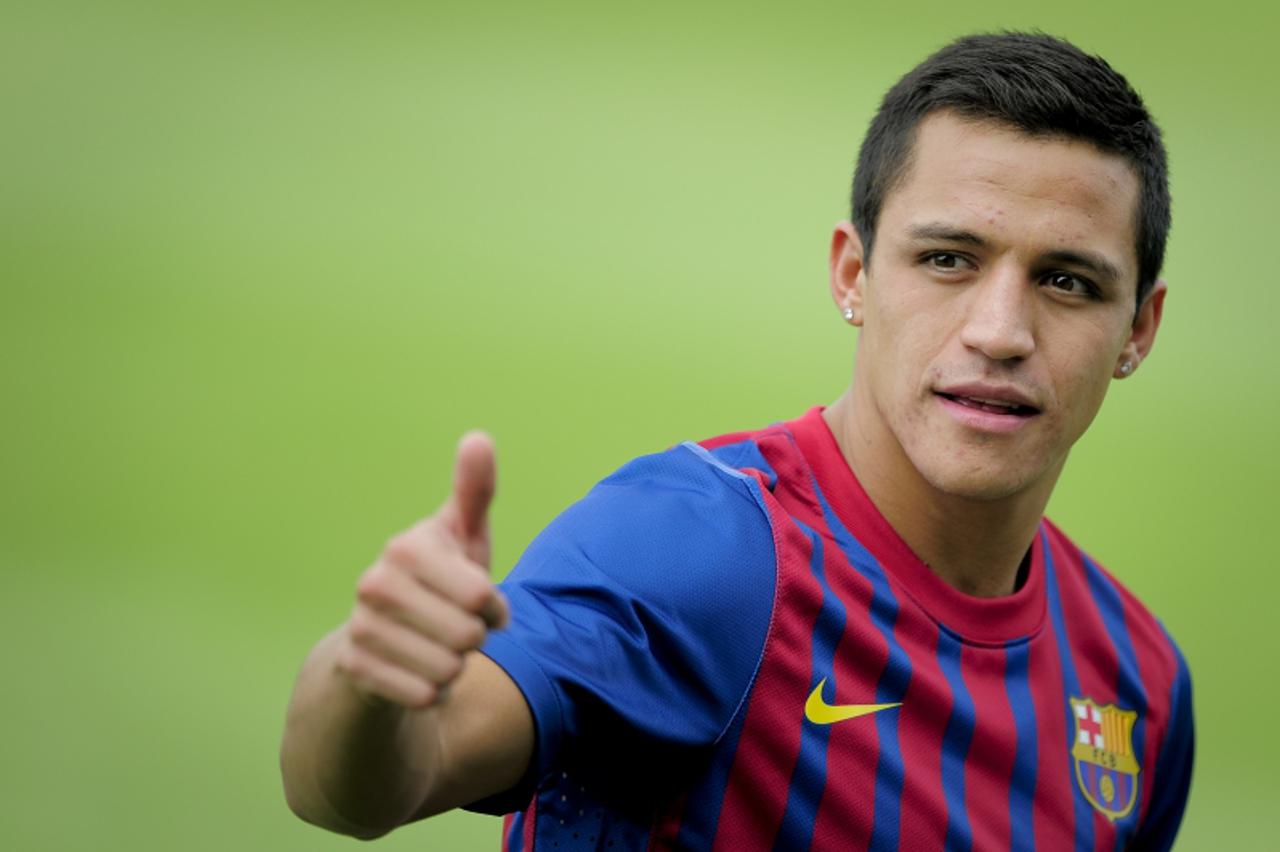 'Barcelona\'s Chilean new player Alexis Sanchez gives a thumb up during his official presentation after signing a new contract with the Catalan club on July 25, 2011, at the Sports Center FC Bacelona 