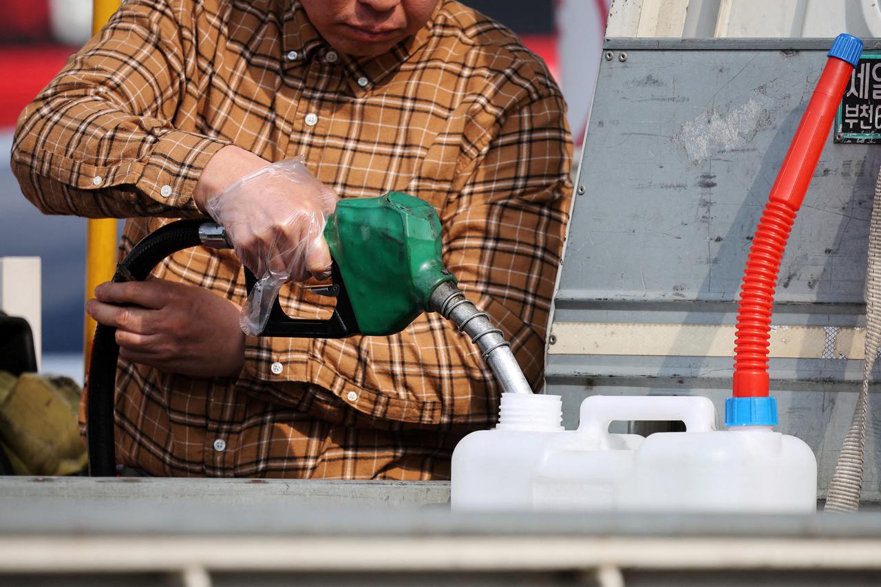 People fill up their car at a gas station in Seoul