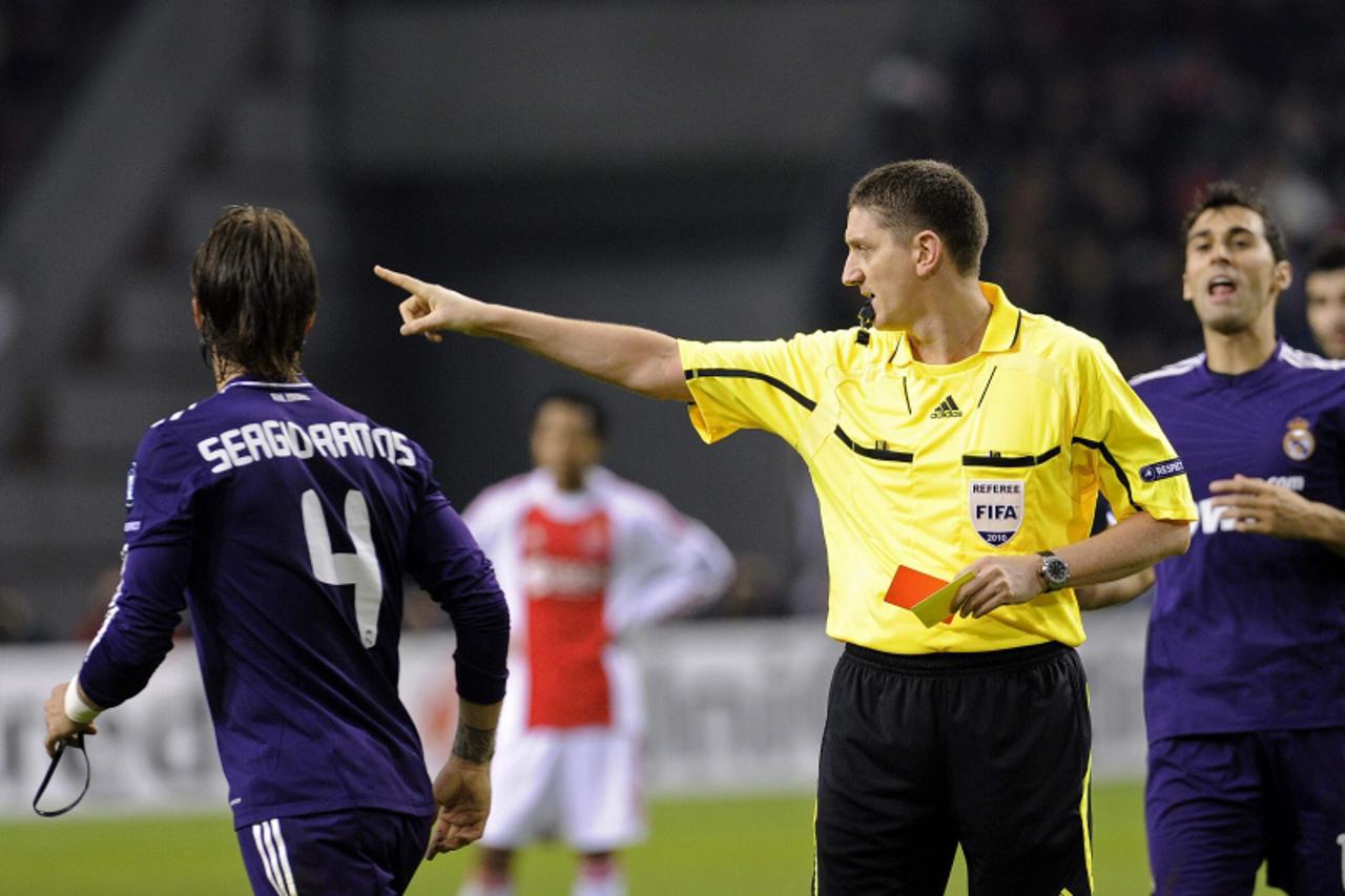 \'Real Madrid\'s Sergio Ramos (L) receives the red card from referee Craig Thomson during their Champions  League Group G soccer match against Ajax Amsterdam in Amsterdam November 23, 2010.    REUTERS
