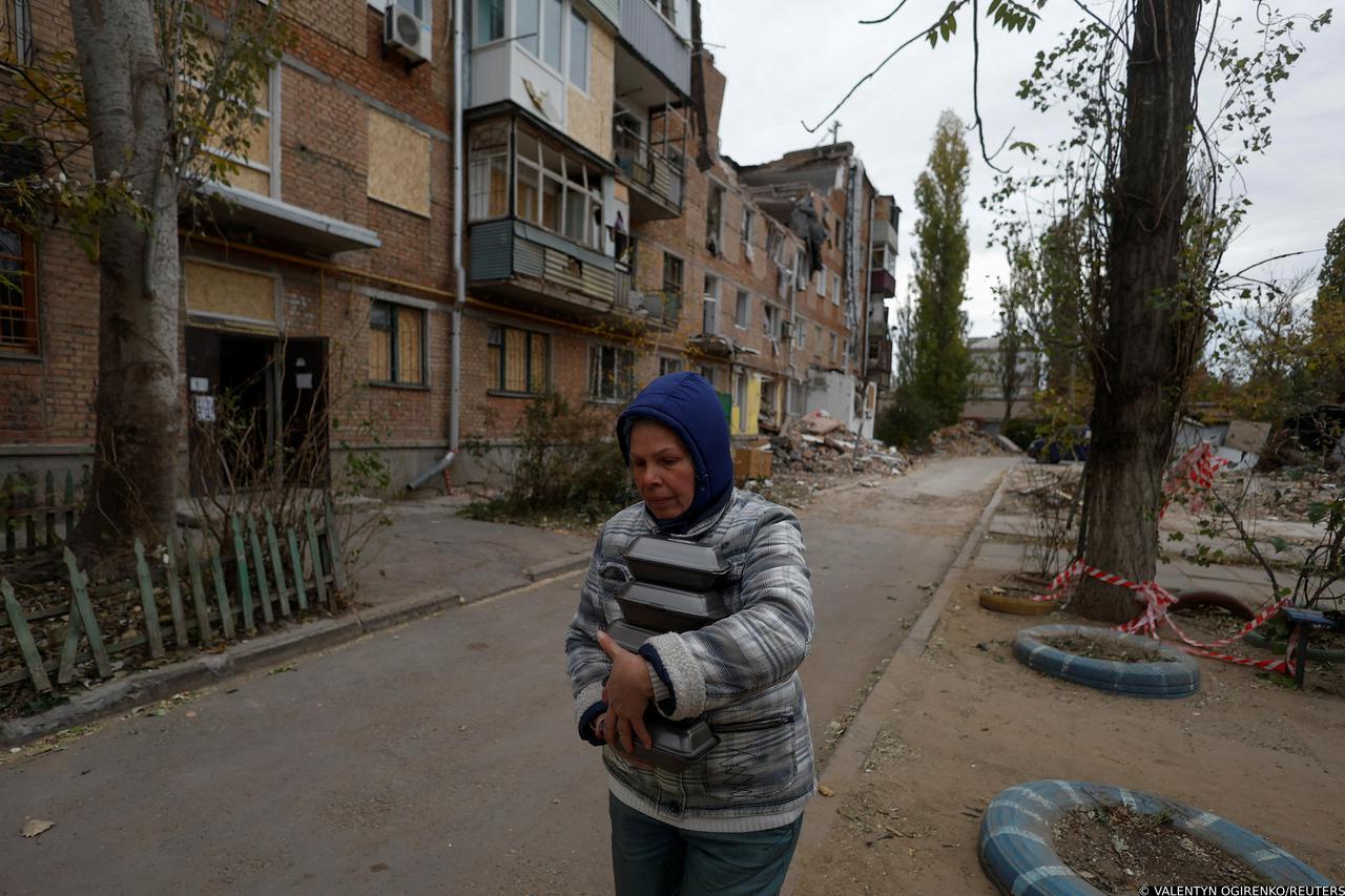 Local resident Tetiana Honcharova carries meals, provided by the NGO World Central Kitchen, to her neighbours during an electricity power cut in Mykolaiv