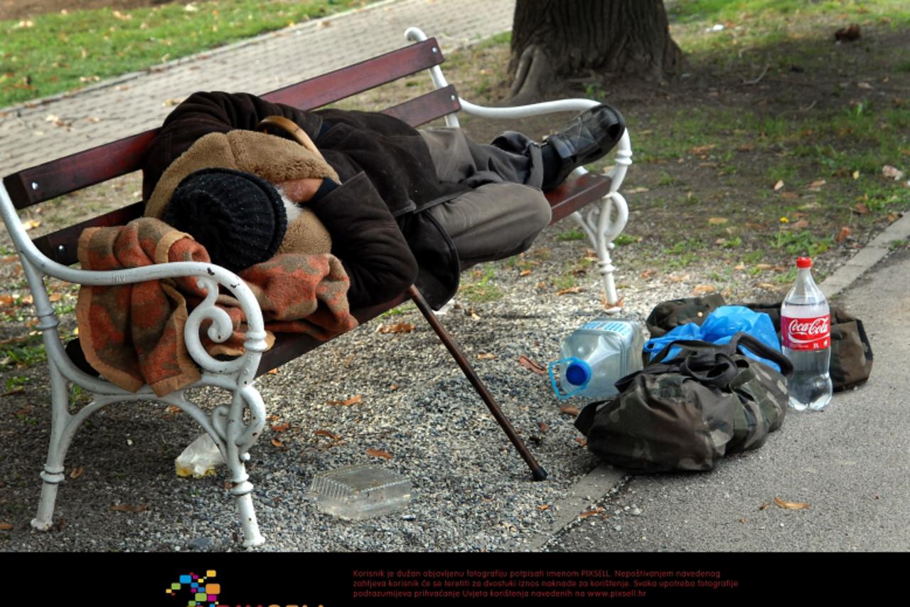 '08.10.2012., Slavonski Brod - Starac beskucnik spava na klupi u parku. Zbog hladnoce ogrnuo se kaputom, a dekicu je stavio pod glavu. Uz njega na zemlji, u dvije torbe stoje njegove stvari i boca vod