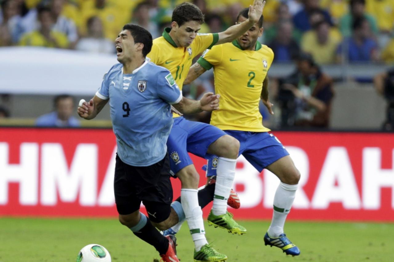 'Uruguay's Luis Suarez (L) reacts as he is challenged by Brazil's Oscar and Dani Alves (R) during their Confederations Cup semi-final soccer match at the Estadio Mineirao in Belo Horizonte June 26, 