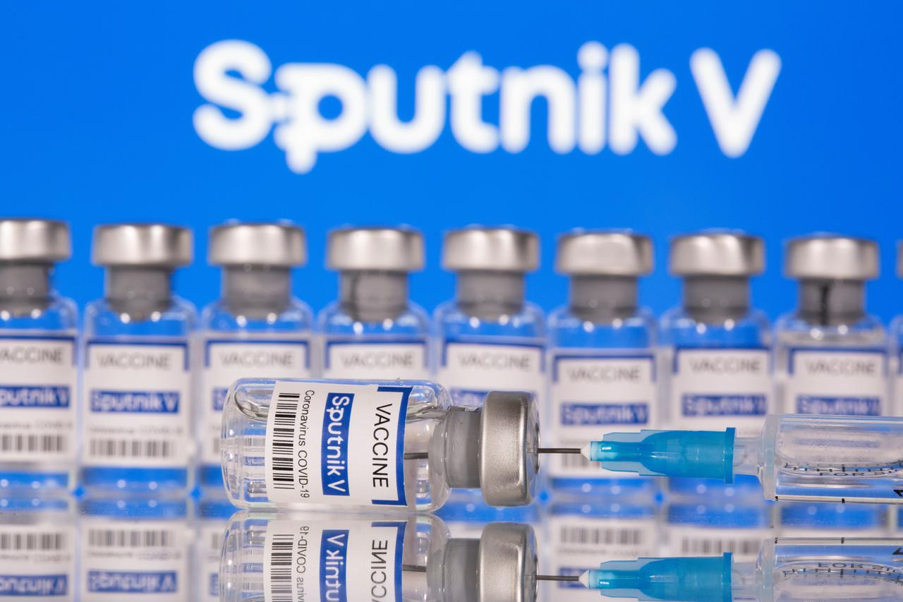 Vials labelled "Sputnik V Coronavirus COVID-19 Vaccine" and a syringe are seen in front of a displayed Sputnik V logo, in this illustration photo