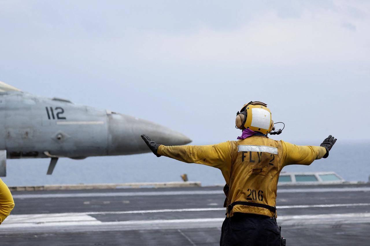 A flight operating crew  membersignals a F/A-18E Super Hornet fighter jet on the flight deck of the USS Dwight D. Eisenhower (CVN 69) aircraft carrier in Southern Red Sea