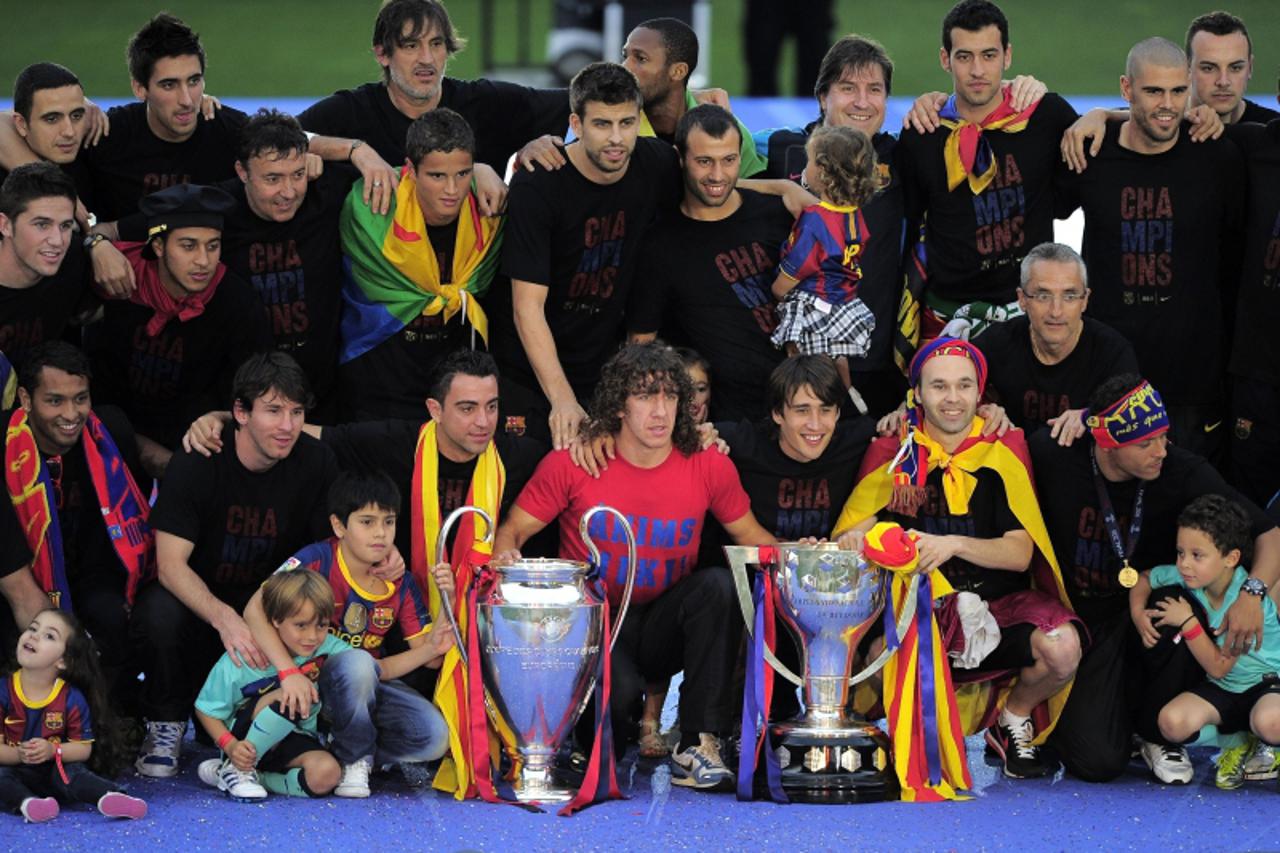 'Barcelona\'s players poses with their Champions League (L) and Liga winners\' trophies during a celebration with supporters at the Camp Nou stadium in Barcelona on May 29, 2011 a day after the team w