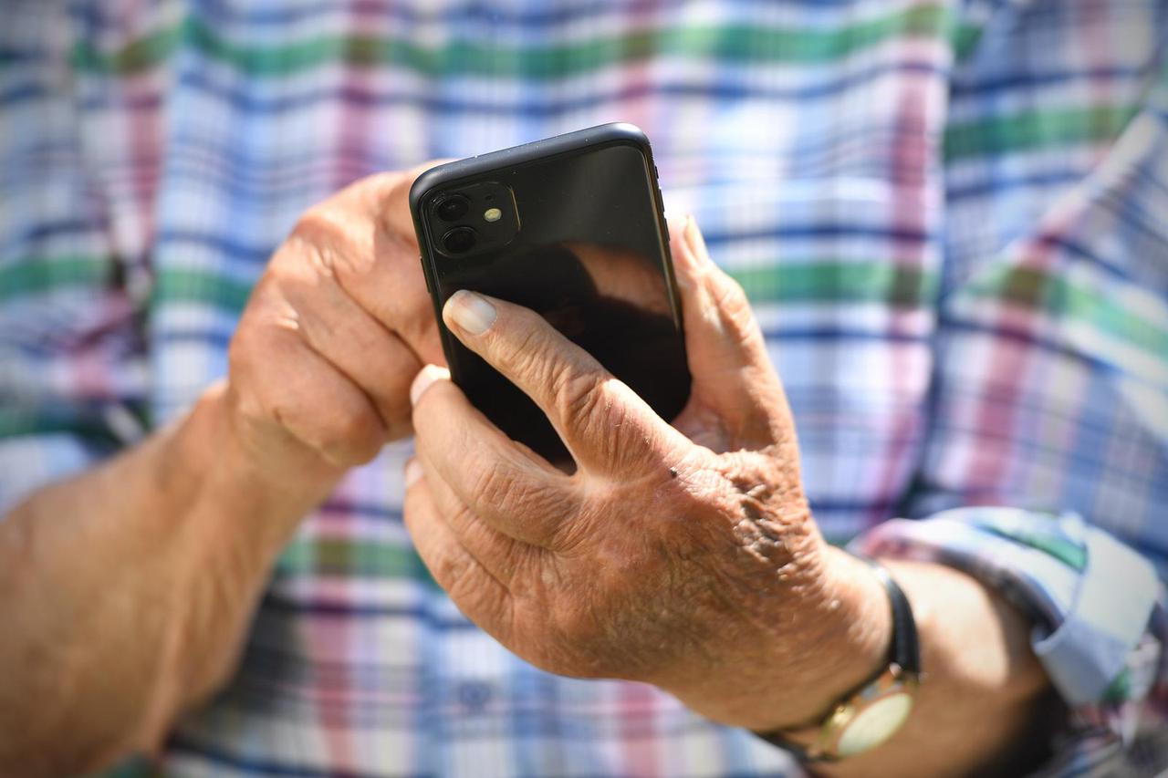Ruestiger old man (92 years) taps on a smartphone.