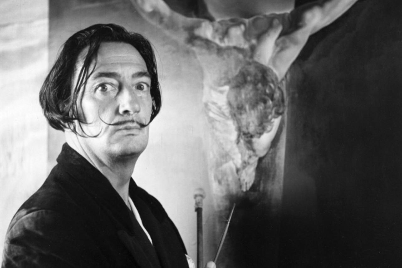 'Spanish surrealist painter Salvador Dali (1904-1989) in his studio in Port Lligat with his painting of Christ on the cross.  Original Publication: Picture Post - 5587 -  We Visit Dali - pub. 1951  Or