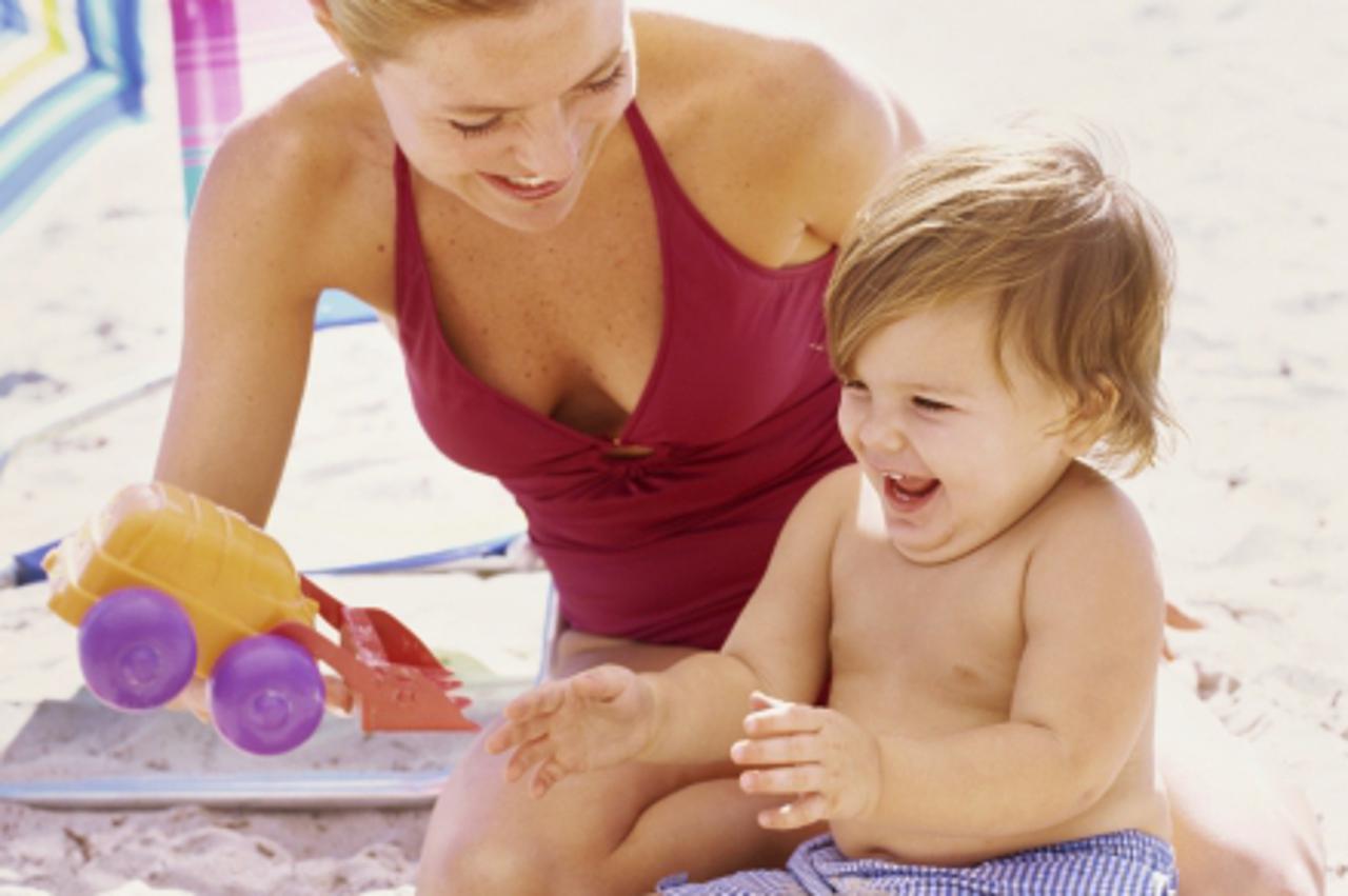 'Close-up of a mother on the beach playing with her baby boy'