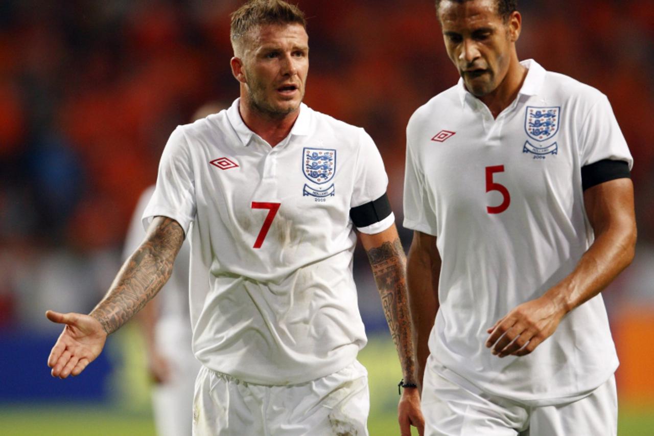 'England\'s David Beckham and Rio Ferdinand react as they leave the pitch at half-time during their friendly soccer match against the Netherlands in Amsterdam August 12, 2009.   REUTERS/Michael Kooren